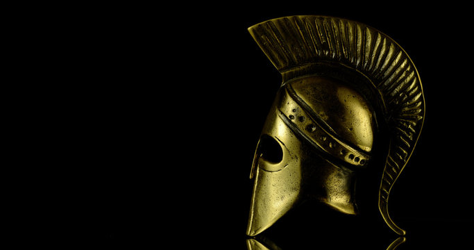 A wonderful golden Spartan helmet as part of the equipment of ancient greek soldiers. King Leonidas and his 300th The piece of metal stands against a black background
