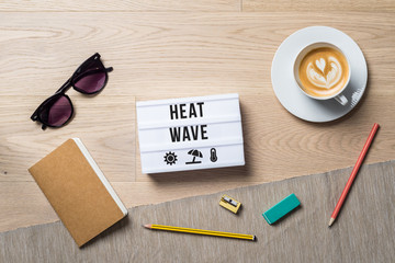 Heat wave written on light box as flat lay from above on office desk