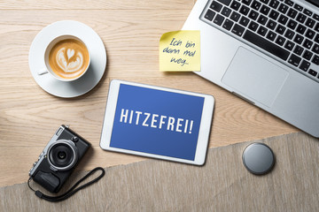Hitzefrei written in german on tablet meaning having time off due to hot weather as flat lay from...