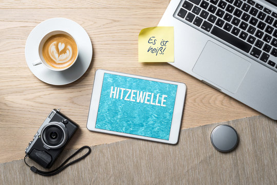 Heat wave written in german on tablet as flat lay from above on office desk