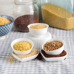 Gluten free grains quinoa, rice, buckwheat, amaranth, millet in bowls on kitchen table. Celiac diet