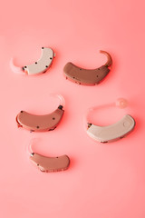 An old analog hearing aids on rink background, alternative to surgery. ENT accessory
