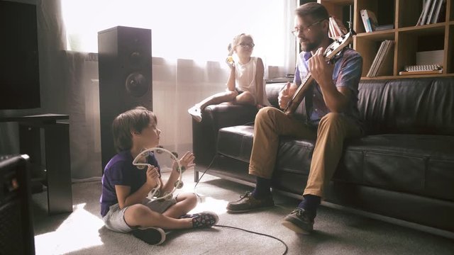 Father plays electric guitar with his children
