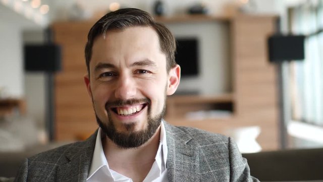 Young handsome businessman smiles looking into the camera, slow motion