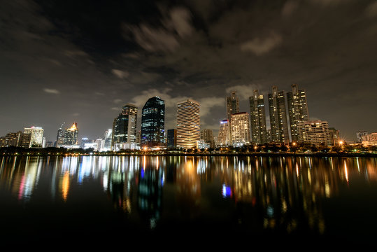 Night Sky of Panorama view , Cloud flow over Modern buildings of Benchakitti Park with lights reflection