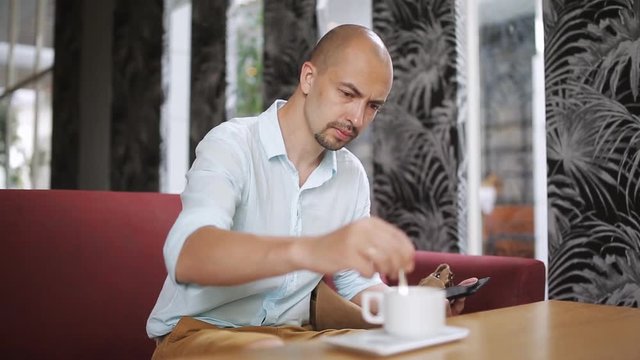 Young man with tablet computer drinking coffee in cafe