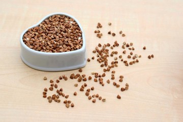 Raw buckwheat in ceramic bowl of heart shape