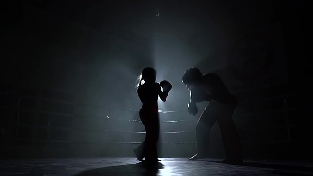 Men with a girl beating in the ring in the dark. Silhouette