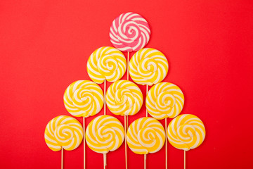 Sweet caramel candy on a red background. Bright lollipops. Yellow and pink sweets from the...