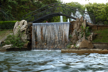 Black metal bridge across decorative fountain with waterfalls in a park in Pyatigorsk, Russia