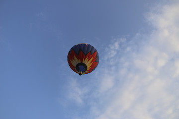 colorful hot air balloon against blue sky. hot air balloon is flying in white clouds. beautiful flying on hot air balloon