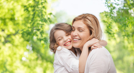 Fototapeta premium family, motherhood and people concept- happy mother and daughter hugging over green natural background