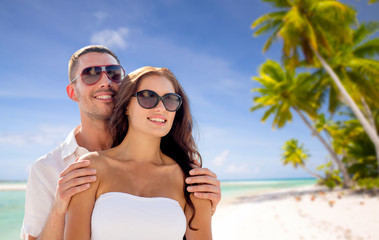 travel, tourism and summer vacation concept - happy smiling couple in sunglasses over tropical beach background in french polynesia