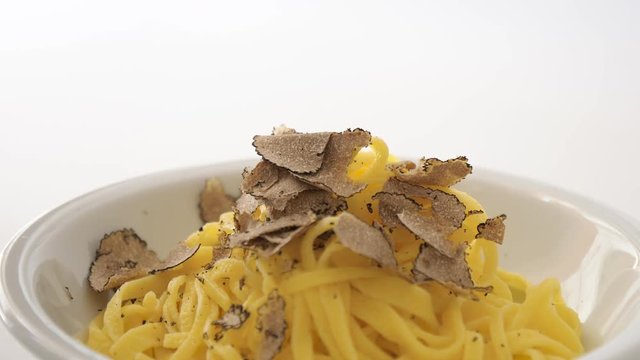 Grated black truffle falling on a plate of Italian fettuccine. Filmed in 4K