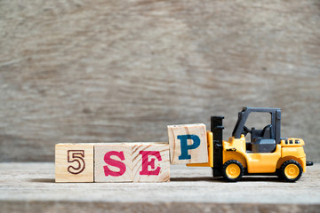 Toy forklift hold block P to complete word 5 sep on wood background (Concept for calendar date in month September)