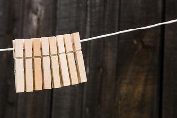 wooden clothespins hang on a rope on a wooden background