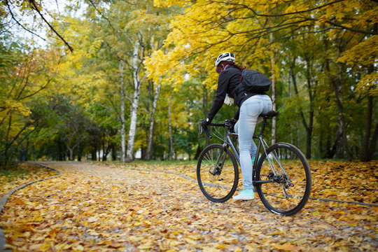 Photo of woman in helmet riding bicycle in autumn