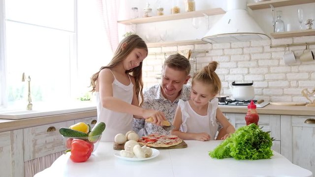 Father and daughters having a fun in the kitchen and making pizza