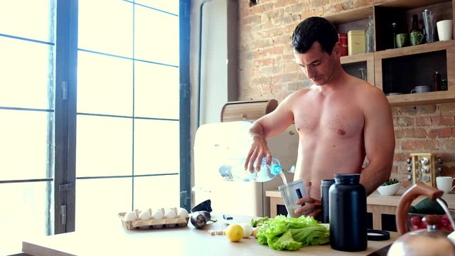 Young attractive man cooks a protein cocktail in the kitchen