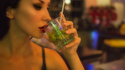 Nightlife. Beautiful Sexy Woman drinking mojito cocktail at the bar