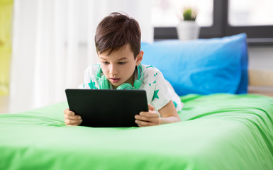 childhood, technology and people concept - boy with tablet pc computer playing game at home