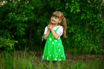 Little girl walk in green garden in sunny summer day