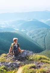 Foto op Canvas Young man tourist rest on the top of hill with beautiful valley panorama © Soloviova Liudmyla