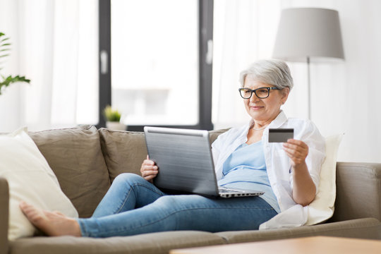 Technology, Online Shopping And People Concept - Happy Senior Woman In Glasses With Laptop Computer And Credit Or Bank Card At Home