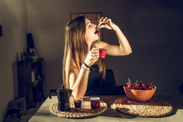 Woman eating cherries and drinking coffee