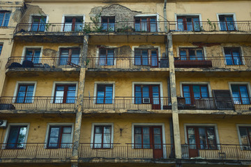 Obraz premium Old collapsing apartment building. The wall of the building, Windows and balconies