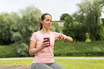 fitness, sport and healthy lifestyle concept - woman with smoothie or shake in plastic cup looking...