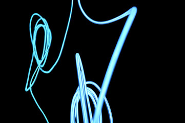 Semi-transparent five millimeters, light glowing wire electro-luminescent cable with neon, white neon light and color on a black background