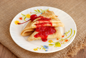 Pancakes with jam. Maslenitsa. Three thin pancakes on a saucer. Pancakes with jam on burlap. Pancakes for breakfast.