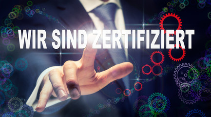 A businessman pressing a We Are Certified "Wir sind Zertifiziert" button in German on a futuristic computer  display