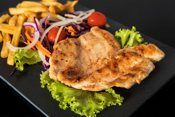 Juicy grilled chicken breast steak with fresh vegetables and french fries