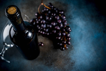 Red wine bottle with glass and grapes, dark background copy space top view selective focus