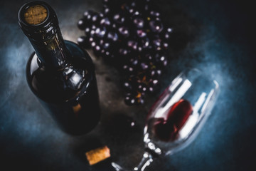 Red wine bottle with glass and grapes, dark background copy space top view selective focus