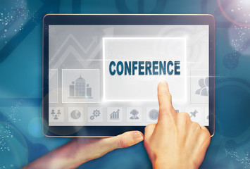 A hand selecting a conference business concept on a computer tablet screen with a colorful background.