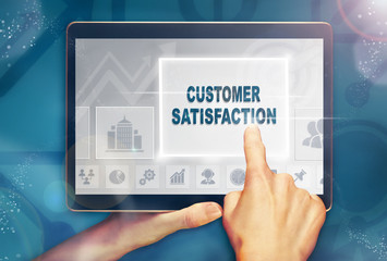 A hand selecting a customer satisfaction business concept on a computer tablet screen with a colorful background.