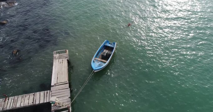 4k aerial video of lonely fishing boat and wooden pier in turquoise ocean, sea. 