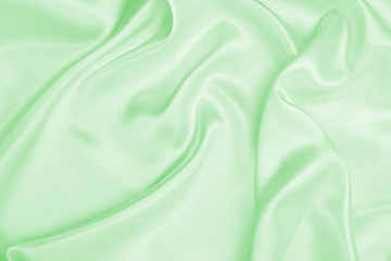 Smooth elegant green silk or satin luxury cloth texture as abstract background. Luxurious background design