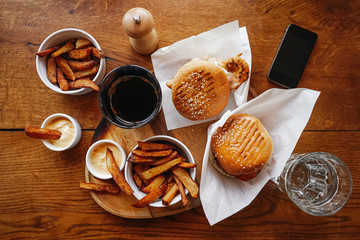 Two juicy burgers, fried potatoes fried in rustic, and fizzy drinks. Fast food, top view.
