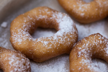 Homemade donuts with icing sugar powder on a wooden background