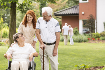 Nurse and grandmother in the wheelchair next to elderly man with walking stick