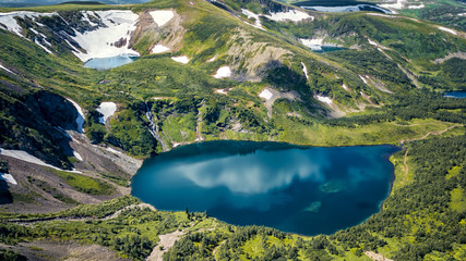 Blue lakes in the mountains snow and green grass Ivanovo lakes