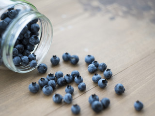 Blueberry in the glass jar at wooden background