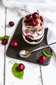 Glass of natural yoghurt with cherries, cherry jam and granola