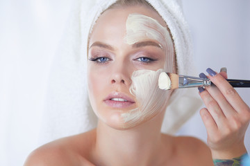 happy woman with a towel on her head puts on face mask