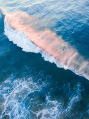 Aerial view of one surfer behind the broken wave.
