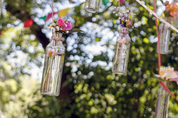floral decoration in the form of glass mini-vases and bouquets of wildflowers hanging from above. Flower vases from bottles with bouquets of colorful flowers. Beautiful decor for the wedding ceremony